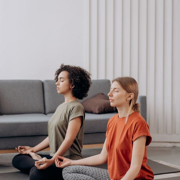 Person sitting in a calm meditation pose in a softly lit room.